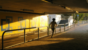 Runner moving through a sunlit urban underpass, representing finding clear pathways and entry points in complex city systems.