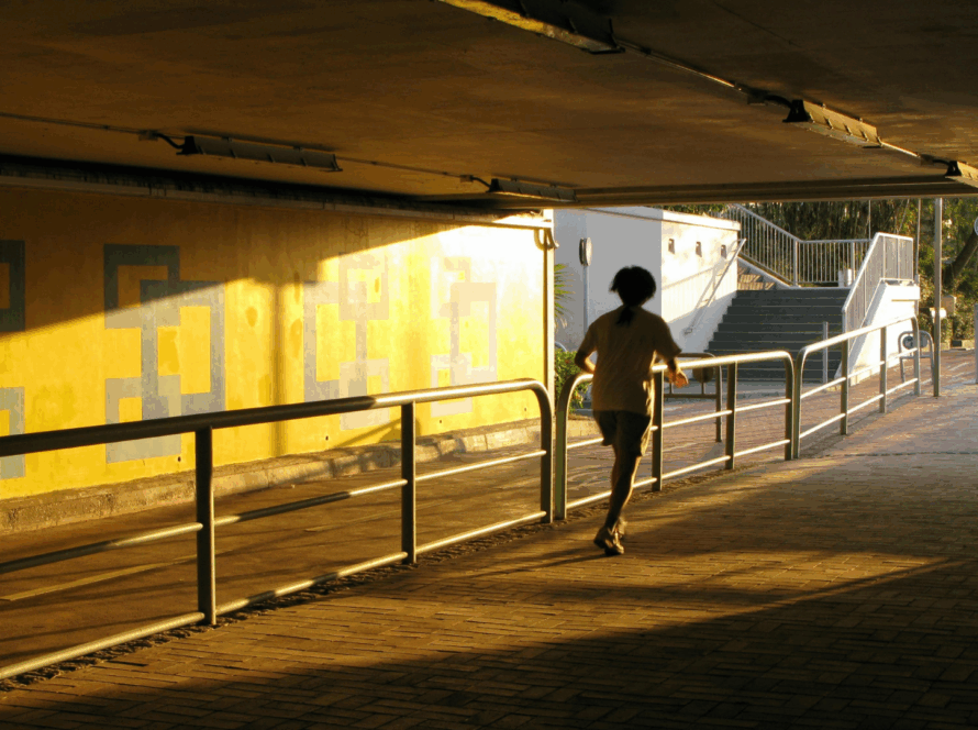 Runner moving through a sunlit urban underpass, representing finding clear pathways and entry points in complex city systems.