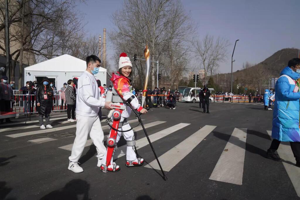 Paralympic torchbearer using an AI-assisted exoskeleton to walk during the Beijing 2022 Paralympic Winter Games.
