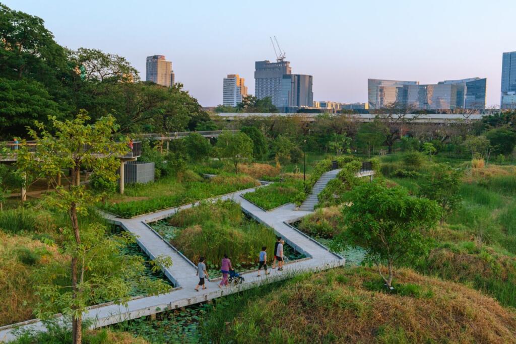 Elevated boardwalk above wetlands at Benjakitti Park allowing public access during seasonal flooding in Bangkok.