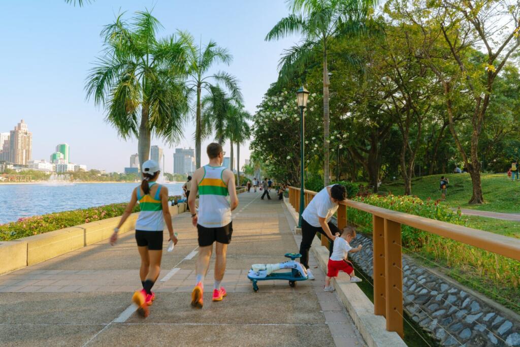 Joggers and families along lakeside promenade at Benjakitti Park in Bangkok